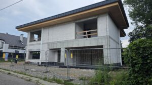 Nowoczesny dom z dachem płaskim i dużymi otworami na przeszklenia w stanie surowym otwartym